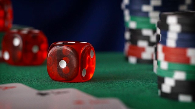 红色骰子在手指中滚动，赌场筹码，纸牌在绿色毛毡上视频素材