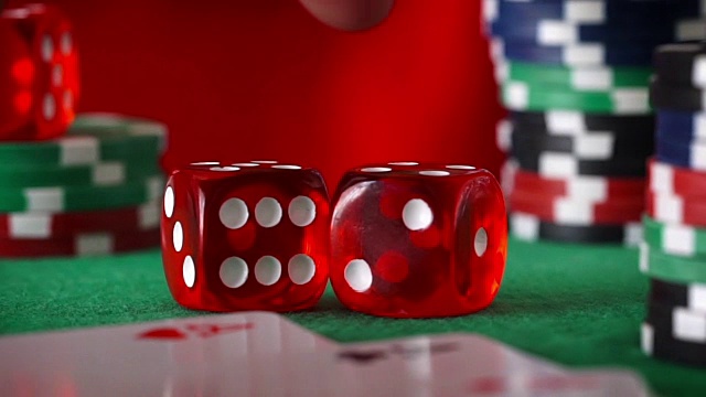 手指上的红色骰子，赌场筹码，绿色毛毡上的纸牌视频素材