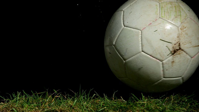 肮脏的足球在草地上滚动视频素材