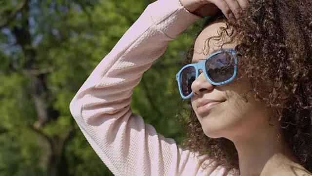 一个美丽的混血女人在太阳眼镜的特写肖像，户外。视频素材