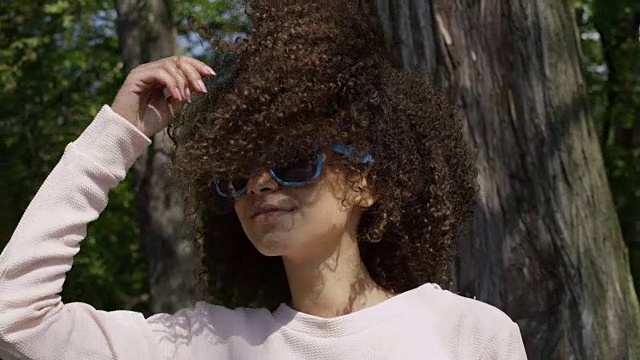一个美丽的混血女人在太阳眼镜的特写肖像，户外。视频素材