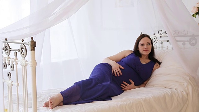 床上有个穿着蓝色裙子的孕妇视频下载