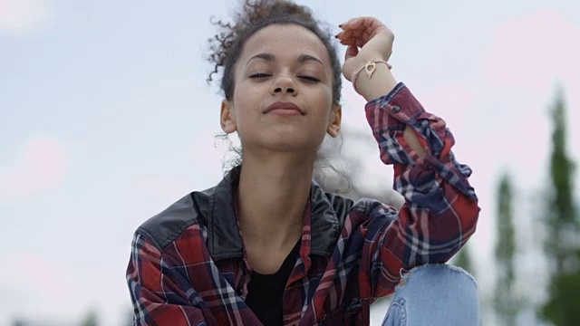 一个年轻的非洲裔美国妇女穿着格子衬衫，在户外的肖像。视频素材