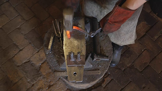 铁匠用叉子把烧红的金属坯弯折视频素材