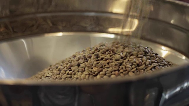 咖啡厂工人将未油炸的咖啡粒放入大铝圆桶中视频下载