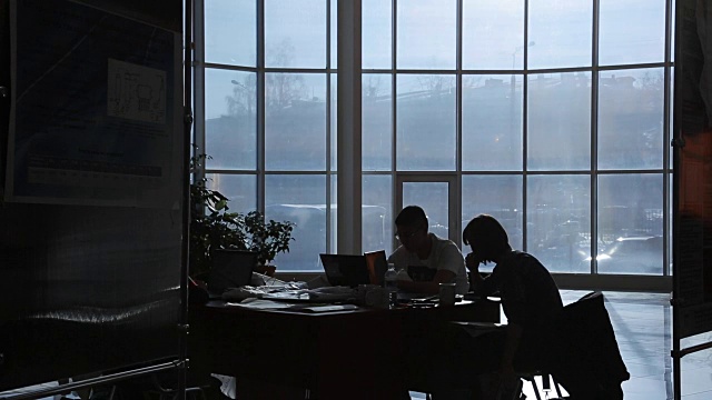 两个商人晚上在黑暗的办公室里工作视频素材