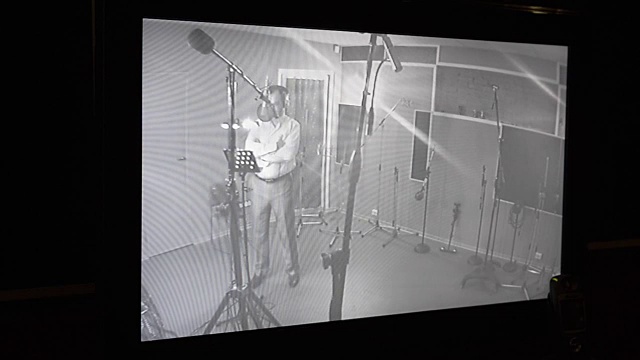 一名男子在录音室里对着麦克风唱歌。监控摄像头。双手交叉视频下载