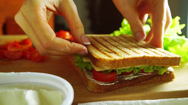 用沙拉叶、果酱、樱桃番茄和奶酪做三明治的女人视频下载