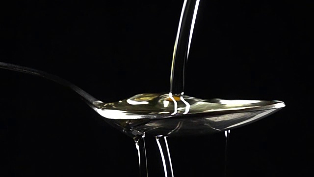 超级慢镜头近距离拍摄葵花籽油被倒在勺子视频素材