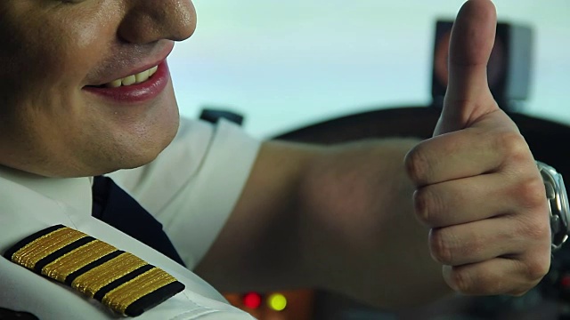 快乐的专业飞行员在驾驶舱内竖起大拇指，享受他的工作视频素材