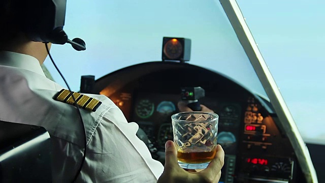 可笑的飞行员坐在驾驶舱里拒绝喝威士忌，生活方式视频素材