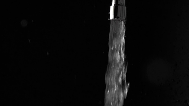 超级慢动作拍摄水从水龙头和飞溅，黑色背景视频素材
