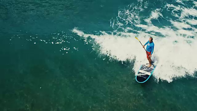 鸟瞰图的冲浪者站起桨板上的蓝色海浪视频下载