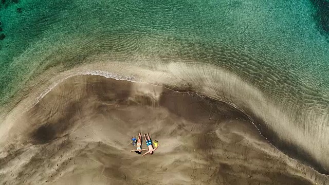 鸟瞰图的年轻夫妇放松在热带海滩度假视频素材