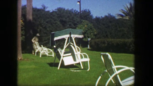 1947年:棕榈树夏季度假休息区绿草草坪椅家具。视频下载