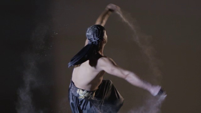 民族舞蹈。在灰色背景上，人与沙共舞。用RED EPIC DRAGON电影摄影机慢动作拍摄。视频素材