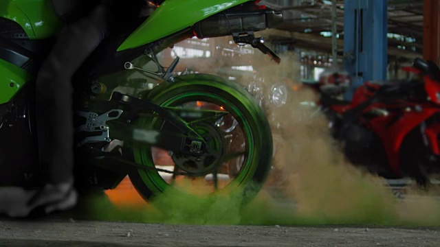 超级运动摩托车做轮胎与彩色的沙子烧坏。缓慢的运动。视频素材