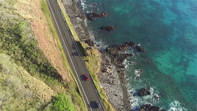 航拍:汽车在海洋悬崖上风景如画的沿海公路上行驶视频素材