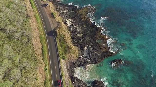航拍:红色敞篷车在海洋悬崖上美丽的海岸公路上行驶视频素材