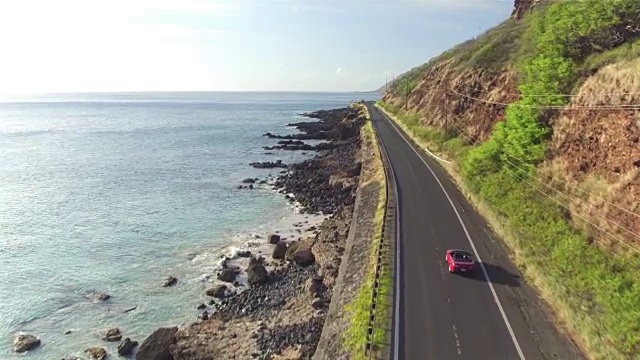 航拍:红色敞篷车沿着风景如画的海岸公路行驶视频素材
