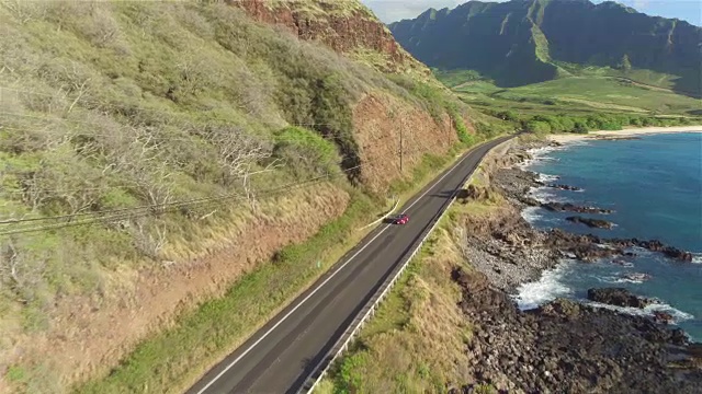 航拍:一辆红色敞篷车沿着火山海岸的海岸公路行驶视频素材