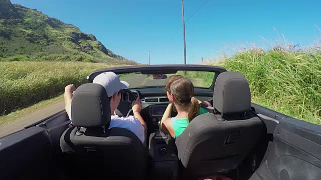近距离观察:快乐的夫妇驾驶红色敞篷车，年轻女子拍照视频素材