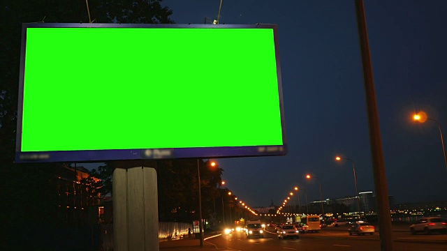 一个在繁忙的夜晚街道上的绿屏广告牌视频素材
