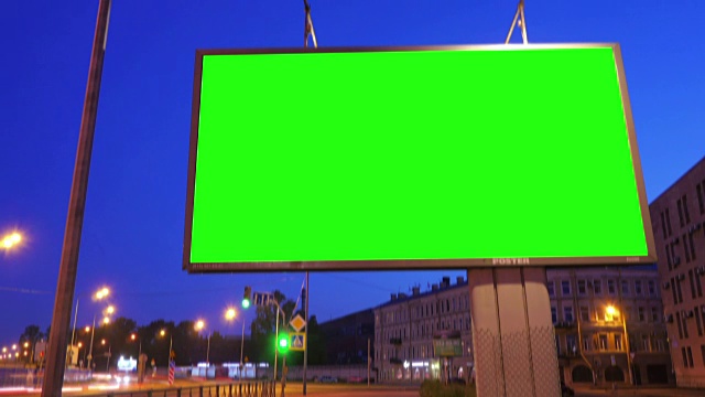 一个在繁忙的夜晚街道上的绿屏广告牌视频素材