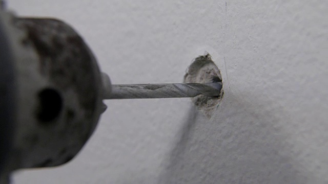 戴头盔的人用电钻在墙上钻洞视频素材