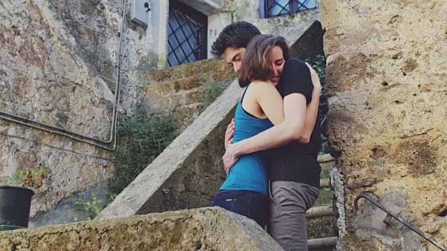 恋爱:害羞的女子在楼梯上拥抱一个年轻男子视频素材