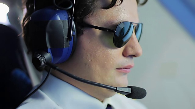 年轻的飞行员戴着墨镜驾驶飞机，很有声望的职业视频素材