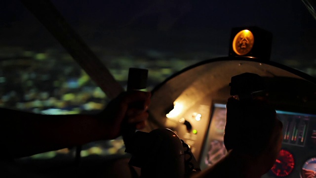 一架商用飞机飞过夜城，飞行员双手放在方向盘上视频素材