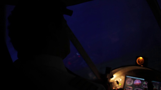飞行员的剪影驾驶飞机和看美丽的夜晚城市视频素材