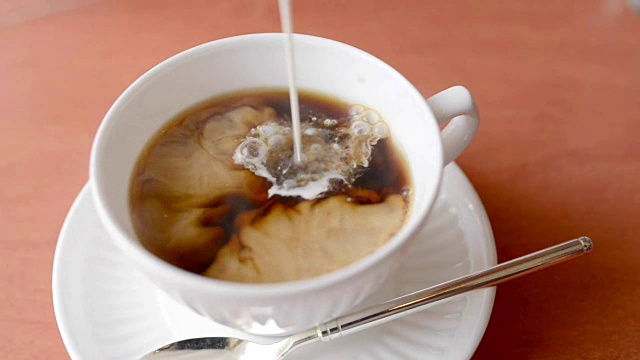 将牛奶倒入白杯中的热红茶中视频下载