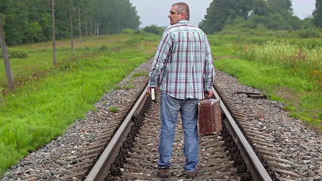 一个人带着书和手提箱在铁路上走了视频下载