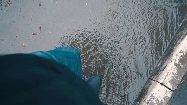 一个男人撑着伞走过雨中的水坑。莫慢，莫慢视频素材