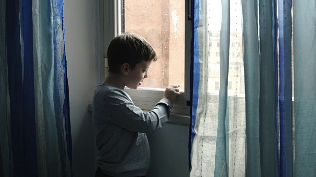 玩着雨滴打在窗户上:下雨天悲伤的小孩子视频素材