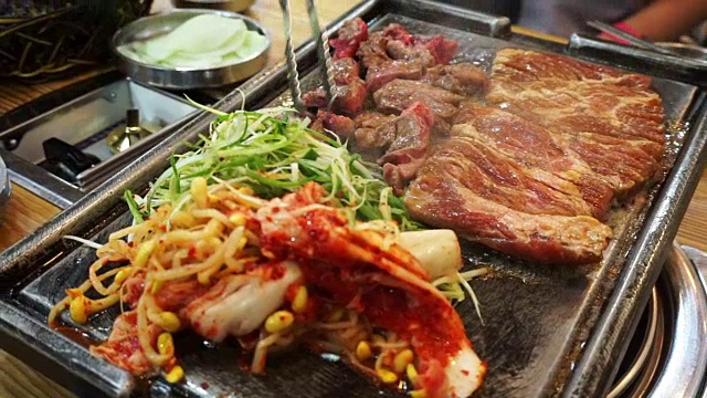 传统的韩国烧烤和配菜蔬菜。烤在大石盘上视频下载