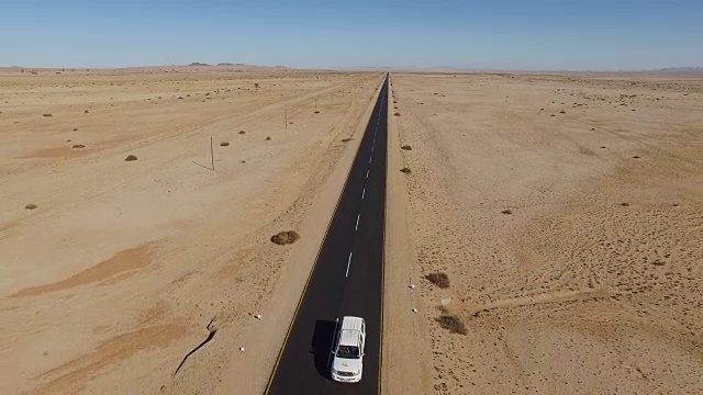 4K鸟瞰汽车行驶在笔直的柏油路穿过纳米布沙漠视频素材