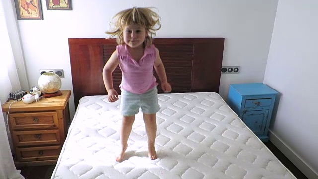 金发宝宝在家里的床垫上跳视频素材