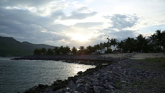 日落在海湾的岩石海岸和棕榈树视频下载