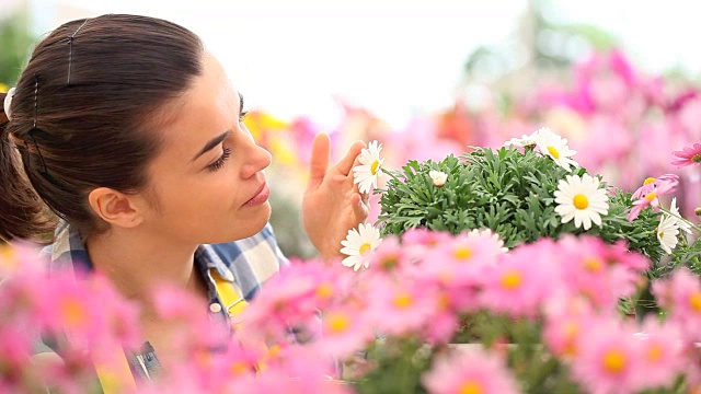 春天微笑的女人闻着花园里的雏菊视频素材