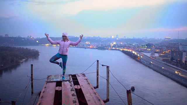 勇敢的年轻女子站在桥的顶端做瑜伽，危险的爱好视频下载