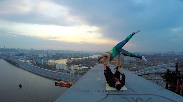 年轻的女人和男人在桥上表演绝技，美妙的城市景色视频下载
