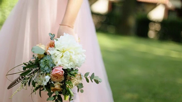 美丽的婚礼花束与白色和粉红色的玫瑰在新娘走在户外视频下载