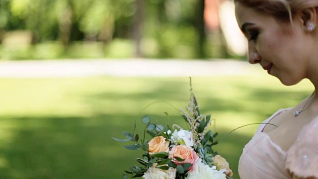 近距离的肖像魔幻美丽的年轻新娘在优雅的服装与花束在公园。看着镜头微笑视频下载