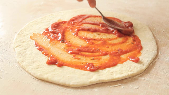 在一家餐馆里，厨师将番茄酱添加到快吃完的披萨上视频素材