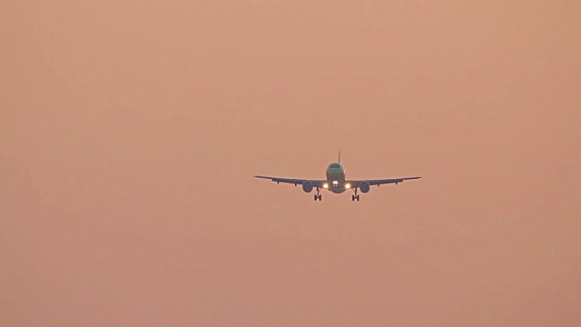 大飞机在日落的天空降落，飞机在红色的日出的天空飞行视频素材