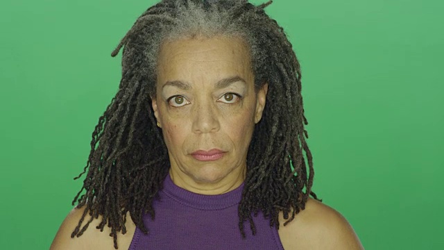 年长的非洲裔美国妇女与长发绺看起来严肃，在绿色屏幕的工作室背景视频素材