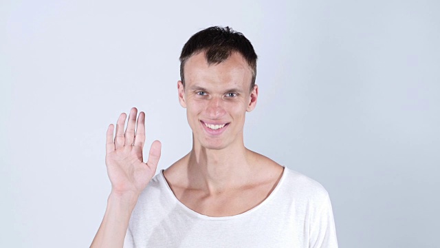 一个微笑的男人的肖像站着，展示他和再见的手势视频下载
